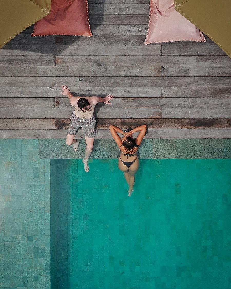 two friends sitting on the pool edge, seen from above